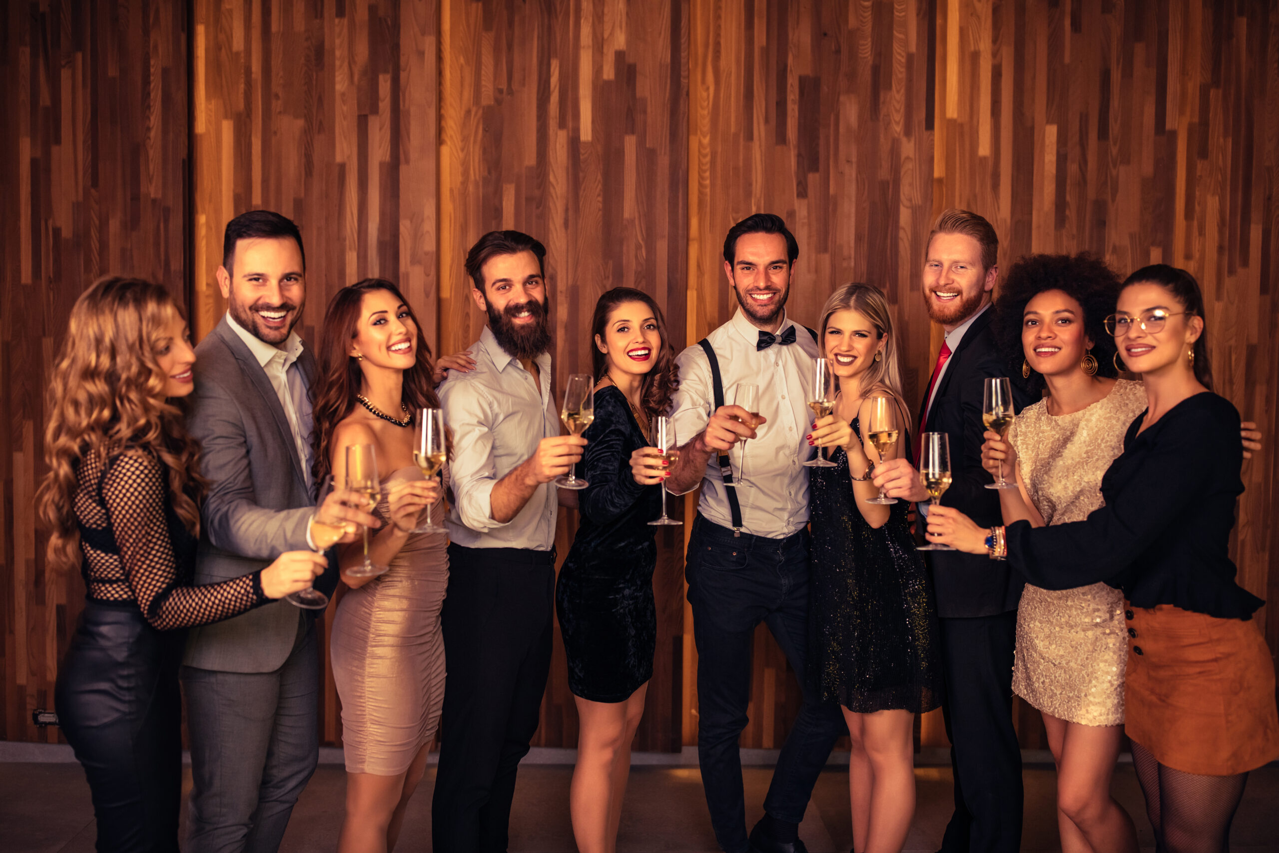 Event photography: Group of people smiling and holding drinks while taking a photo together at an event, captured by professional photographers from Next Chapter Media.