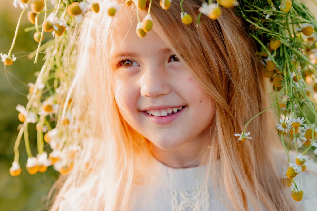 Smiling girl child outdoors enjoying sunshine, captured in children's portrait photography.