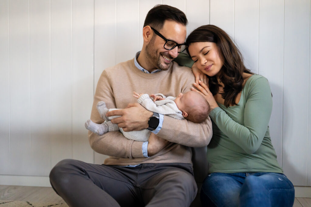 Happy parents embrace their newborn baby during a natural and authentic lifestyle photography session.