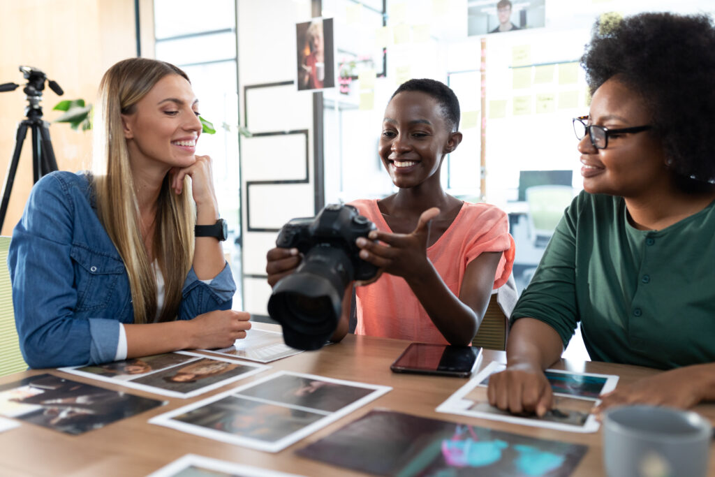 Three girls in a circle, smiling and holding printed photos, showcasing the joy of photography in Boynton Beach