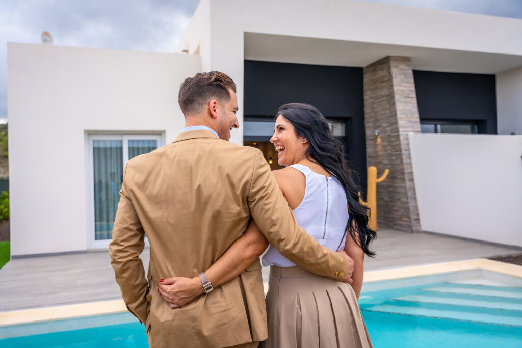 Happy couple embracing by poolside at modern home