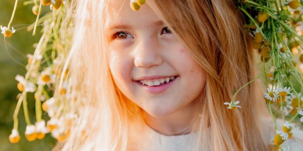 Smiling girl child outdoors enjoying sunshine, captured in children's portrait photography.