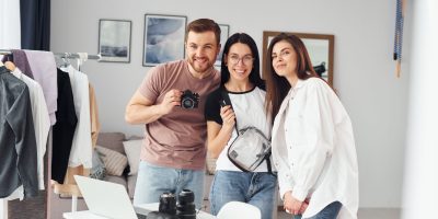 Three diverse photographers connecting with smiles and cameras, highlighting the supportive photography community.