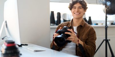 Friendly male photographer smiles while holding a camera, ready to capture your family's story.