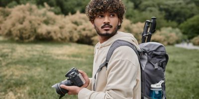 Photographer standing outdoors holding a camera, showcasing essential gear for outdoor photography.